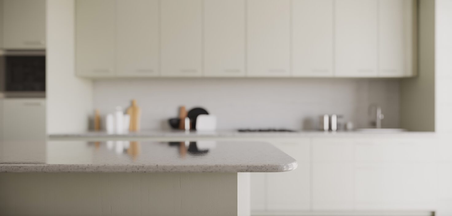 Ett minimalistiskt kök med vita skåp och en spotlight riktad mot en ren bänkskiva, med fokus på minimalism och städning.